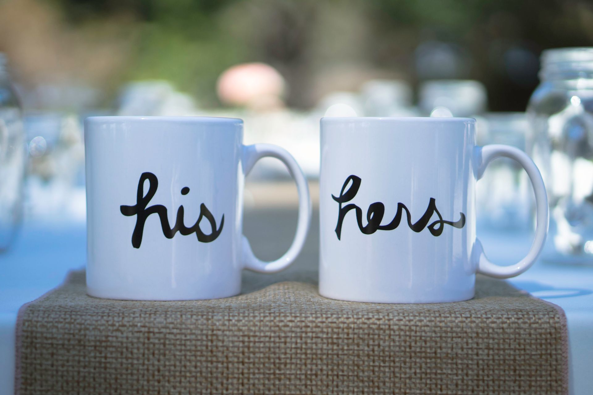 Two coffee mugs with his and hers written on them are sitting on a table.