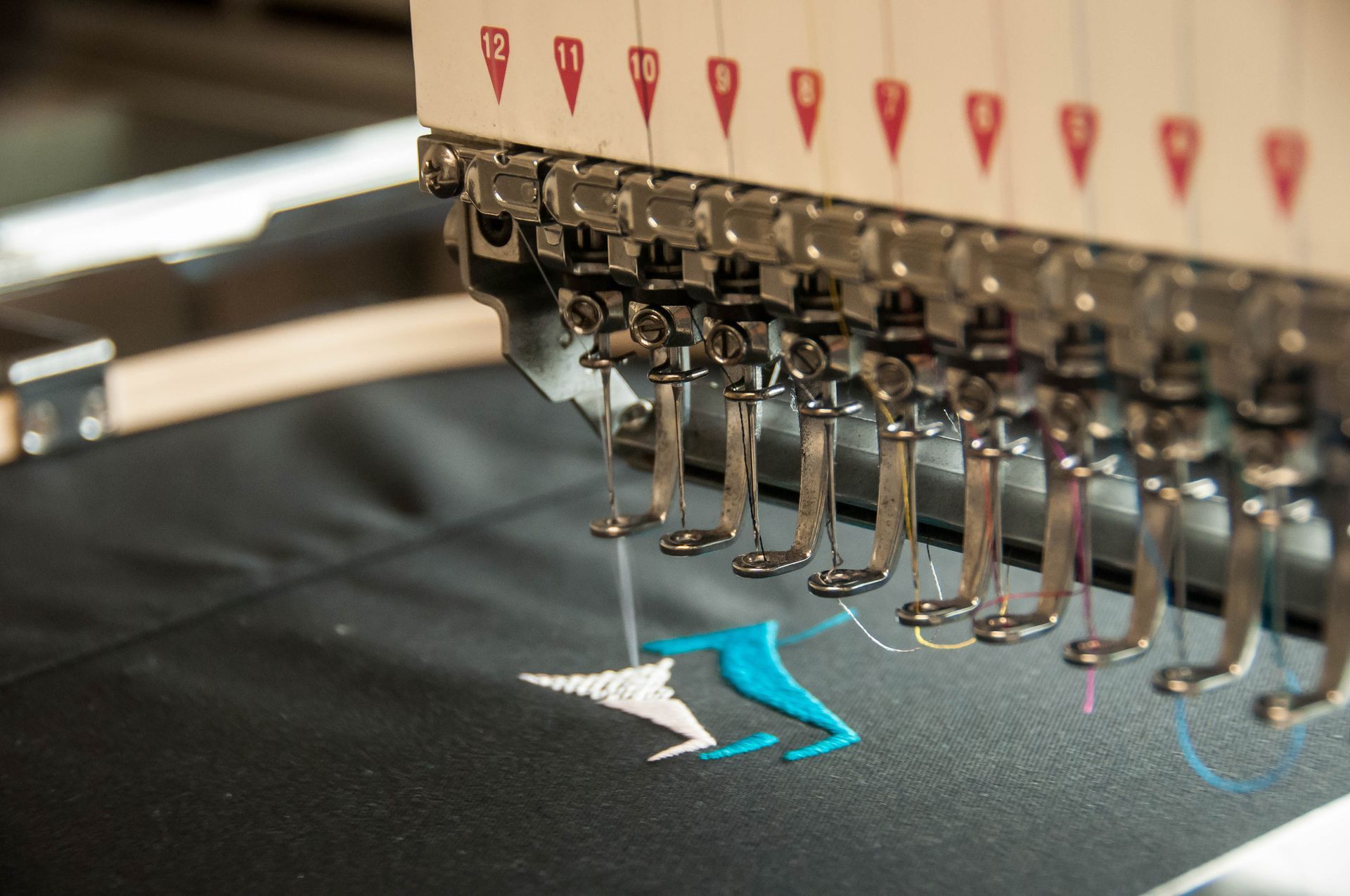 A close up of a machine that is embroidery a logo on a piece of fabric.