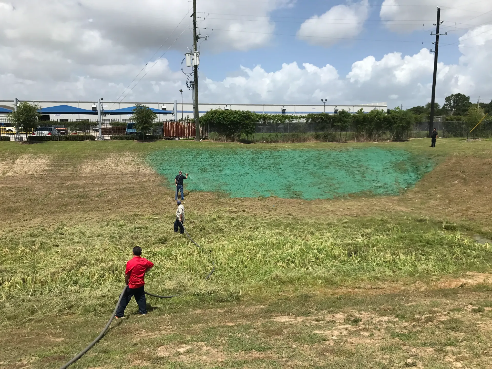 Two people flying a kite in a grassy field under a cloudy sky