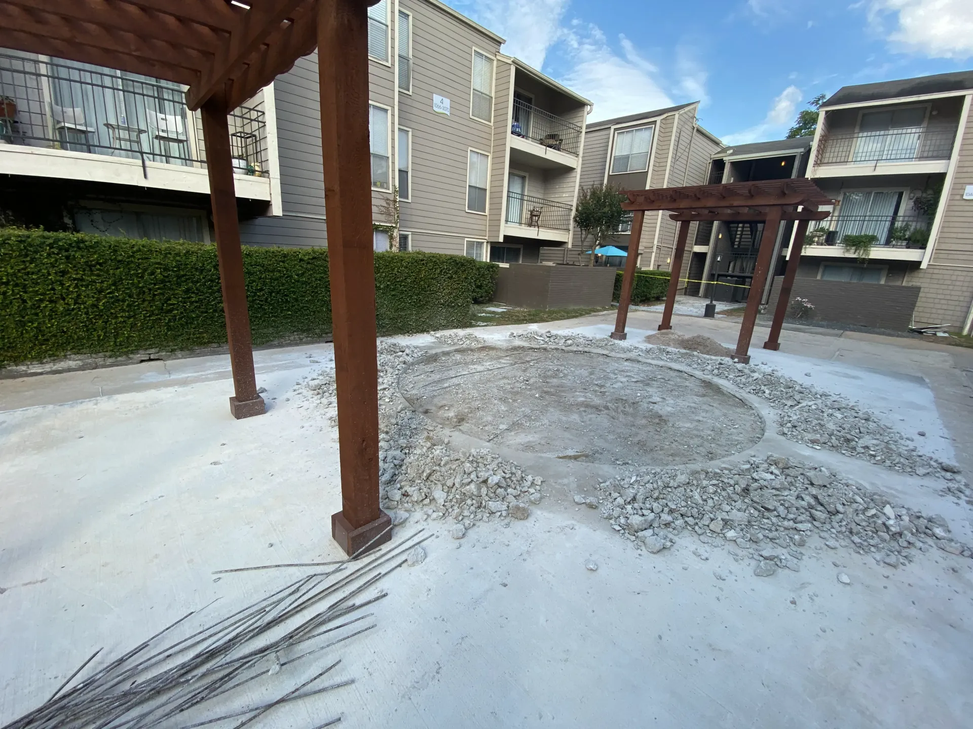Snow-covered courtyard with wooden pergola posts and apartment buildings in the background