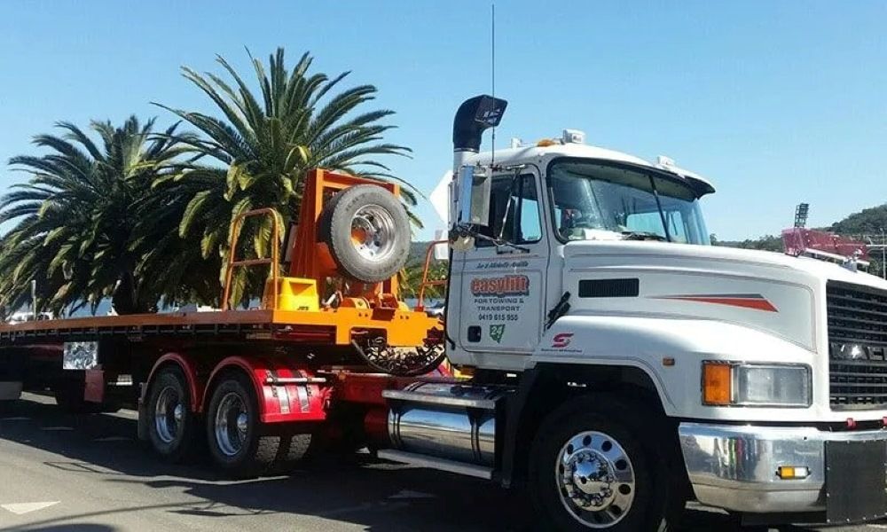 A Mack Truck Is Parked in Front of Palm Trees — Easylift Towing NSW Pty Ltd In Swansea, QLD