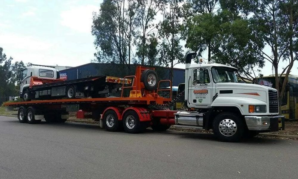 A White Truck with A Flatbed Trailer Is Parked on The Side of The Road — Easylift Towing NSW Pty Ltd In Swansea, QLD