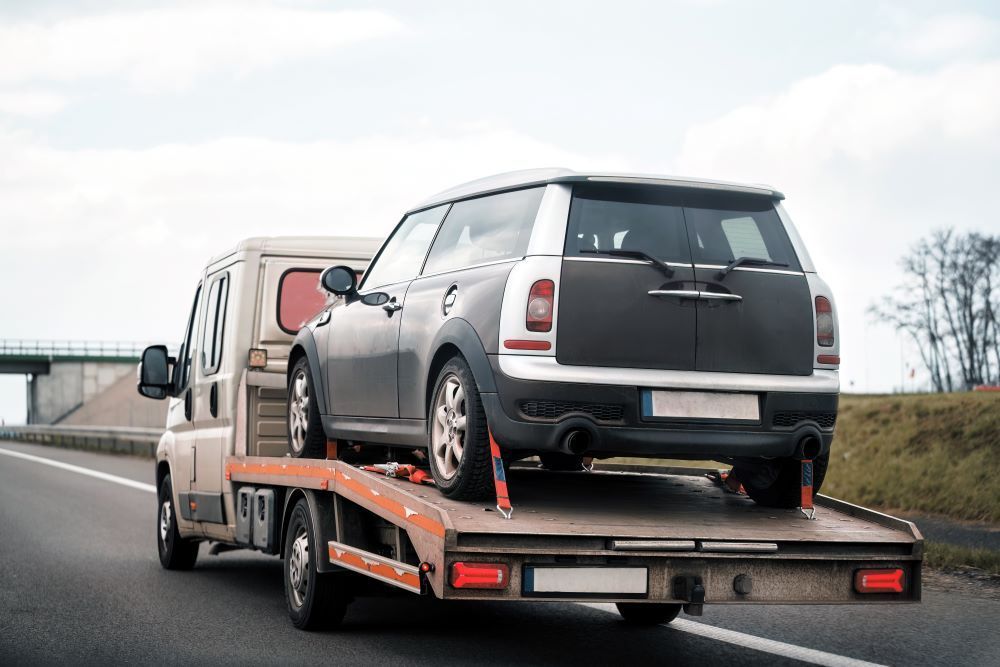 A Tow Truck Is Towing a Small Car on A Highway — Easylift Towing NSW Pty Ltd In Belmont, QLD
