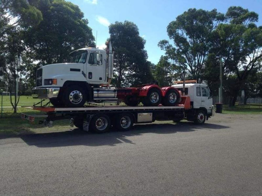 A White Truck Is Being Towed by A Red Tow Truck — Easylift Towing NSW Pty Ltd In Redhead, QLD