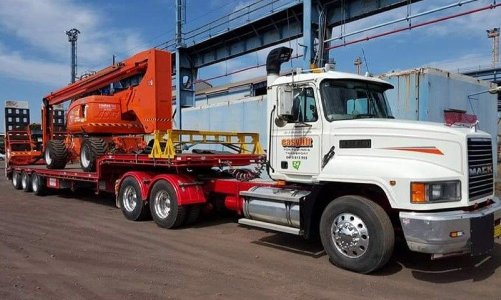 A Semi Truck Is Carrying a Crane on A Flatbed Trailer — Easylift Towing NSW Pty Ltd In Swansea, QLD