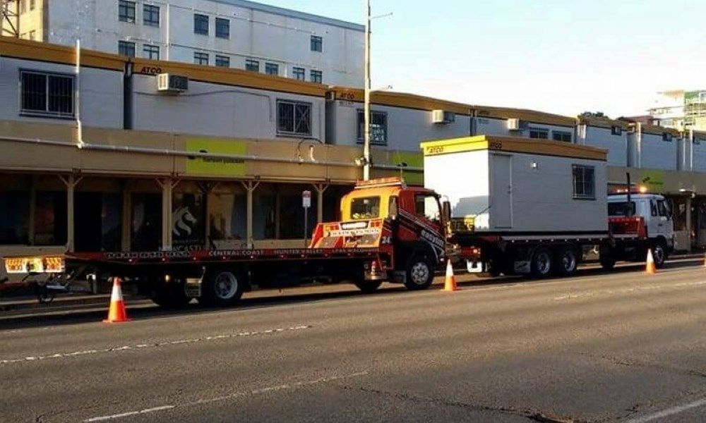 Two Trucks Are Parked on The Side of The Road in Front of A Building — Easylift Towing NSW Pty Ltd In Swansea, QLD