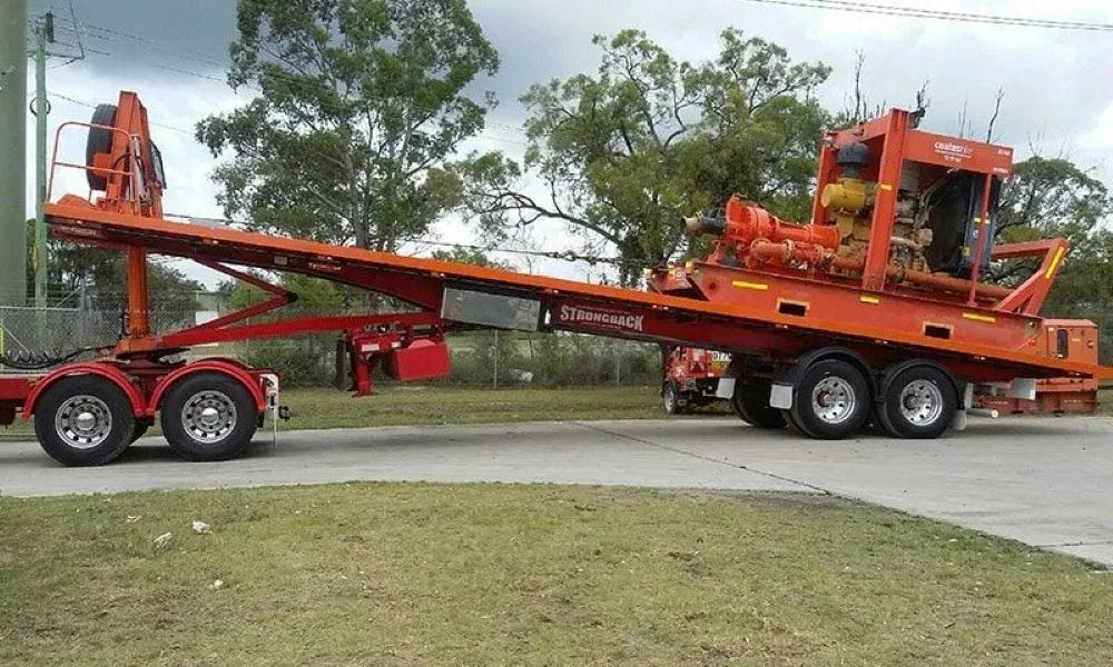 An Orange Tow Truck with A Tractor on The Back Is Parked on The Side of The Road — Easylift Towing NSW Pty Ltd In Cessnock, QLD