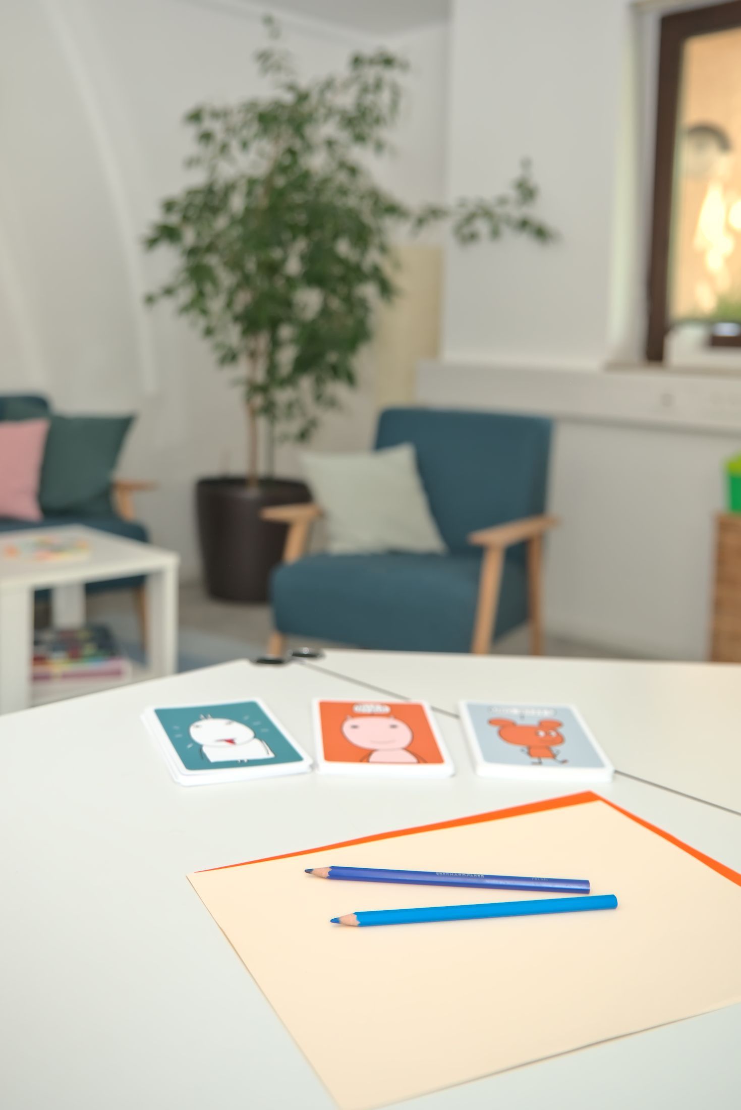 Sprechzimmer, ein Tisch mit Buntstiften und einem Malblock, Spielkarten