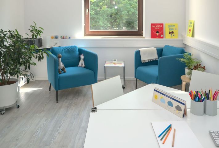 Sprechzimmer, zwei blaue Sessel, Maltisch mit Buntstiften drauf