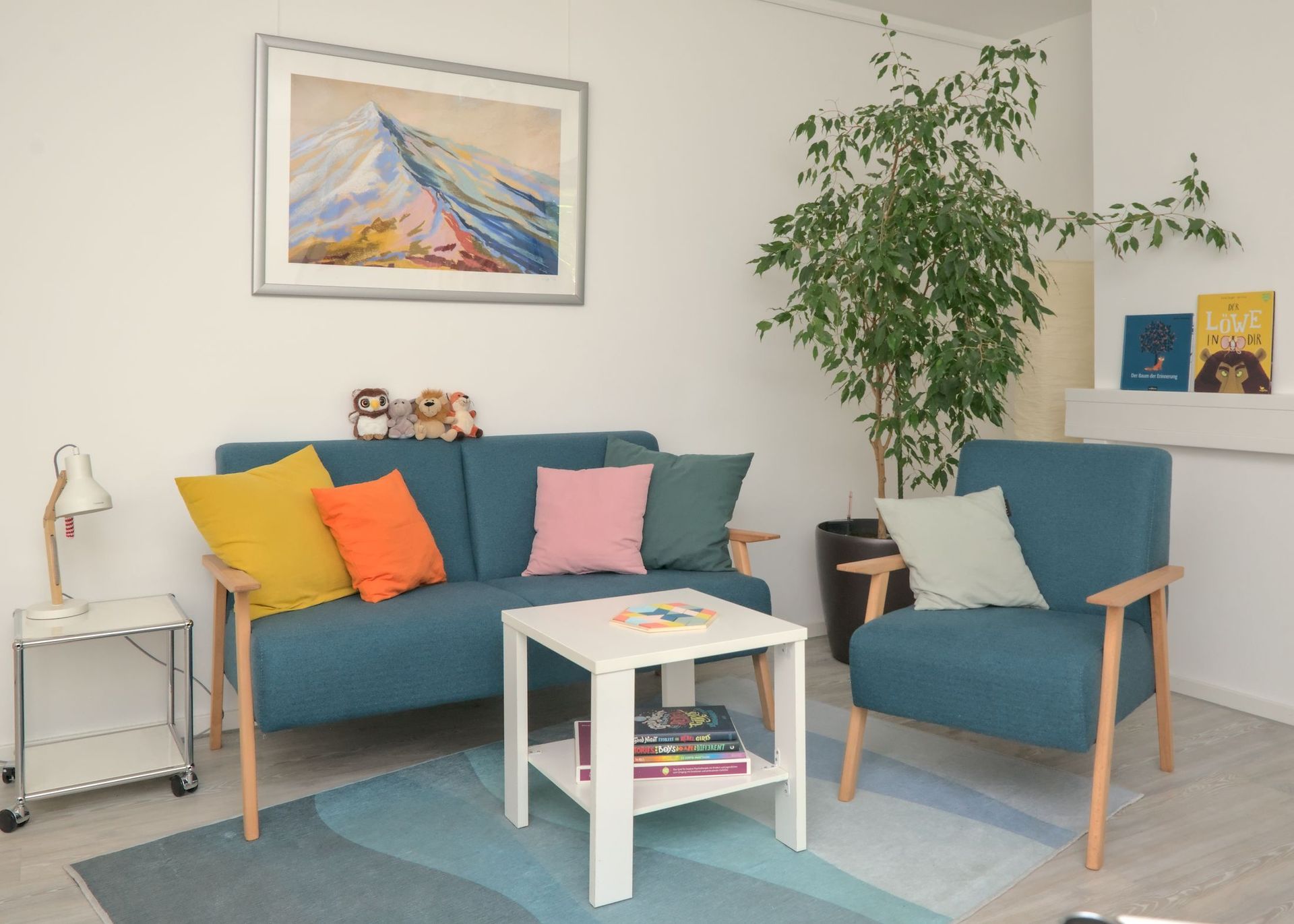 Gemütliches Sprechzimmer mit einer blauen Couch und zei Sesseln