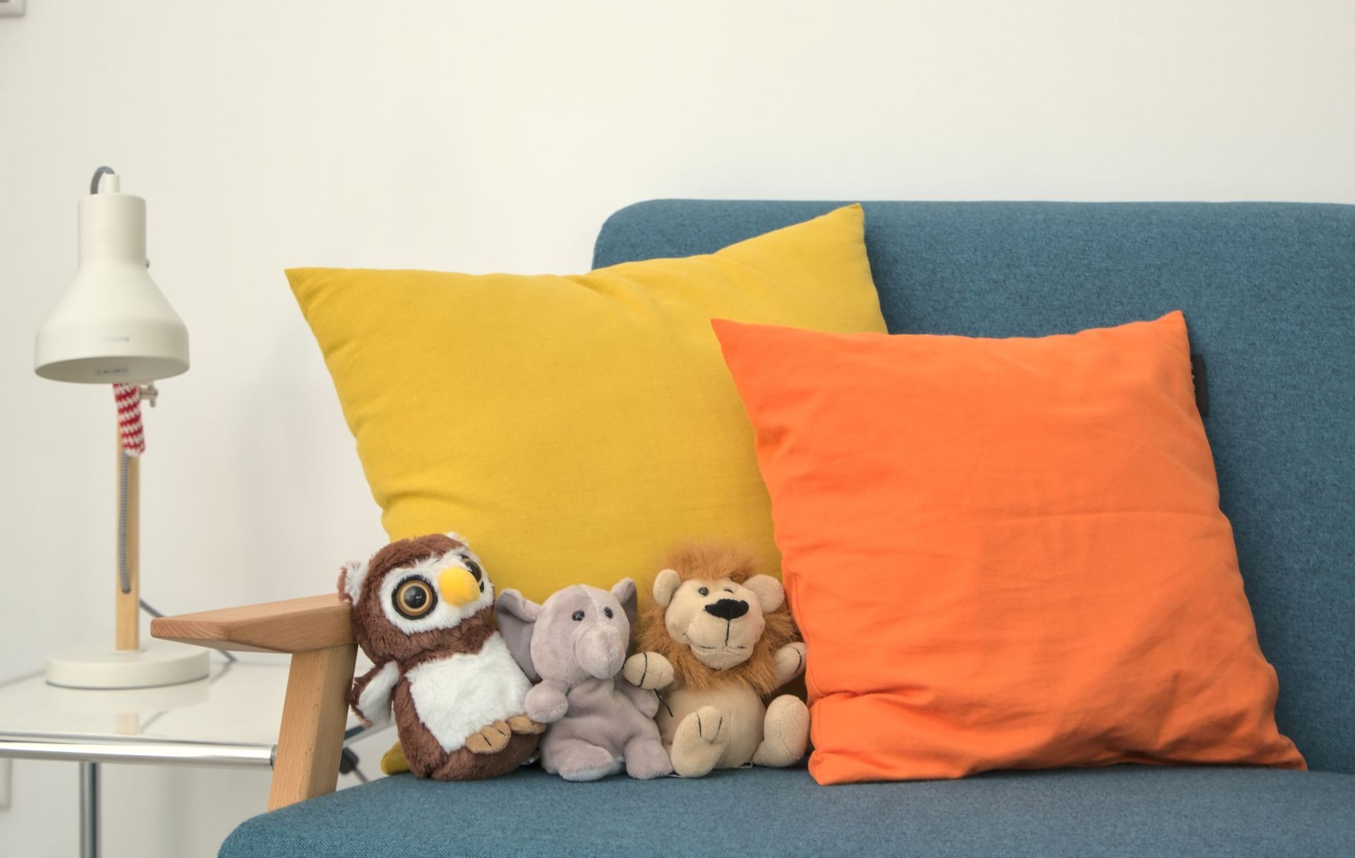 Kuscheltiere auf enem Sofa mit einem orangenem und gelben Kissen