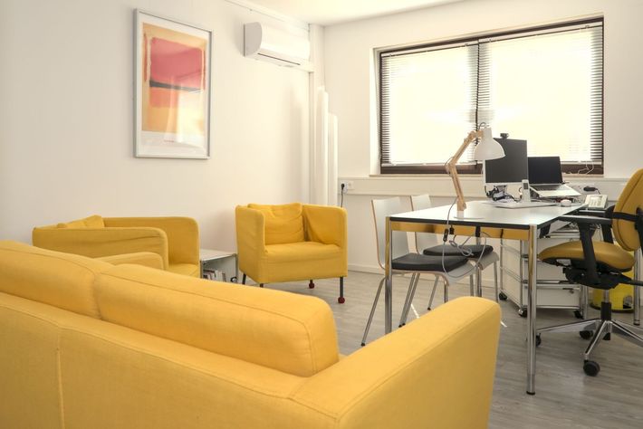 Sprechzimmer mit gelber Couch und zwei gelben Sesseln, Schreibtisch, Computer