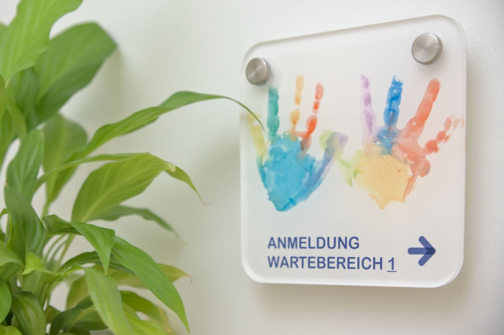 Türschild mit buntem Abdruck der Kinderhände, Hinweis zur Anmeldung und Wartebereich