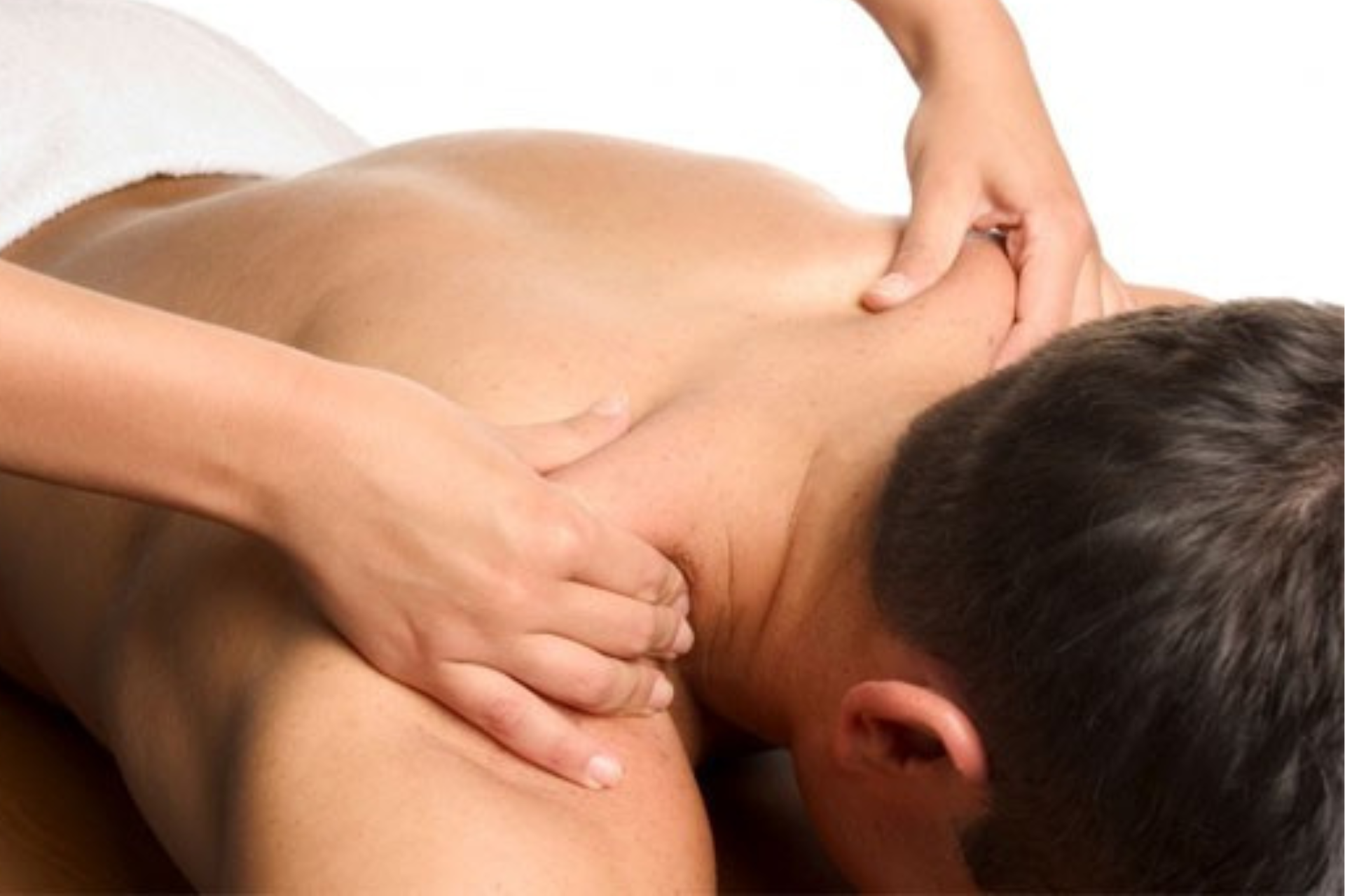 A person receiving a back massage on a white towel, with hands kneading the shoulders and upper back.