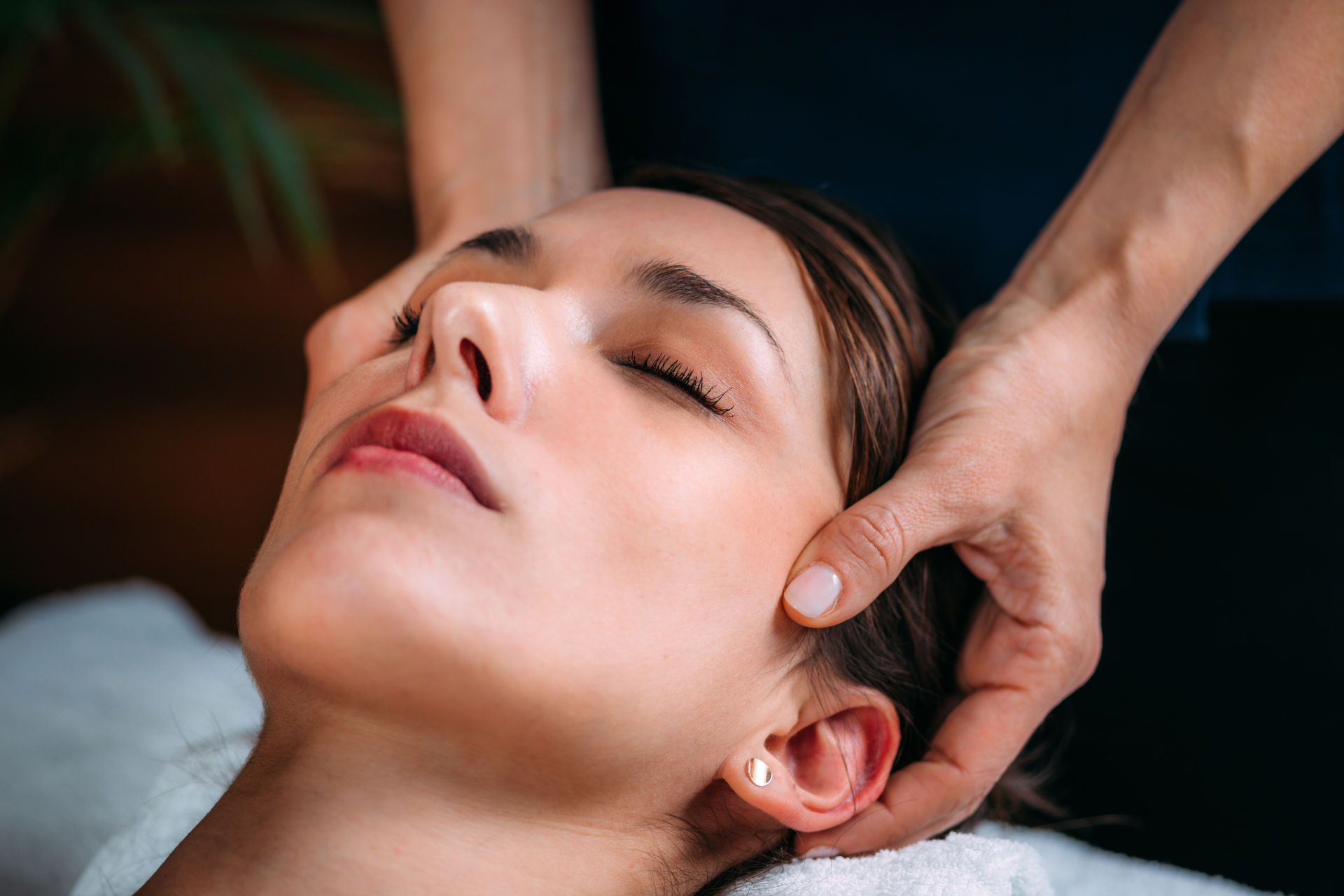 Hands gently massage a woman’s face and temples in a spa treatment