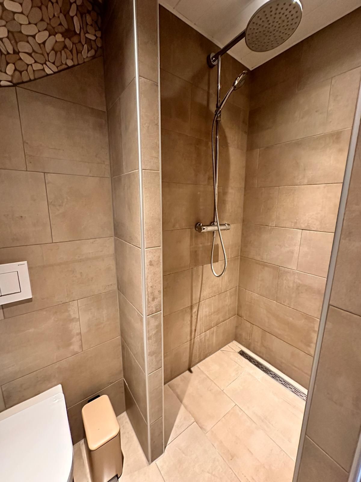 Inloopdouche met neutrale tegels, een rainshower en kiezels.