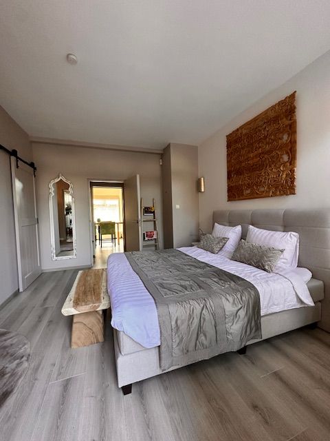 Slaapkamer met groot bed, houten bank en decoratieve wanddecoratie.