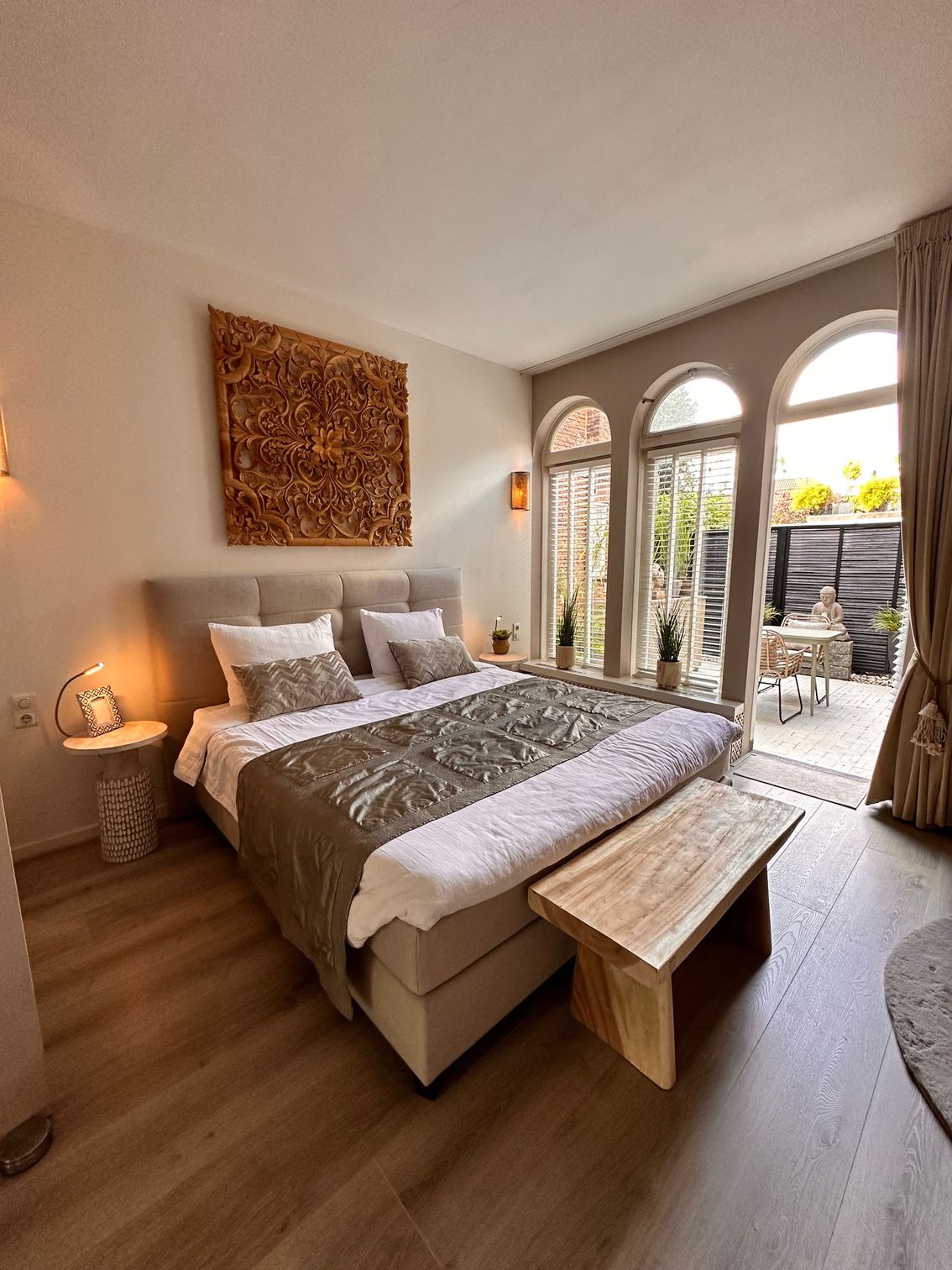 Slaapkamer met een bed, een bank en deuren naar een patio.