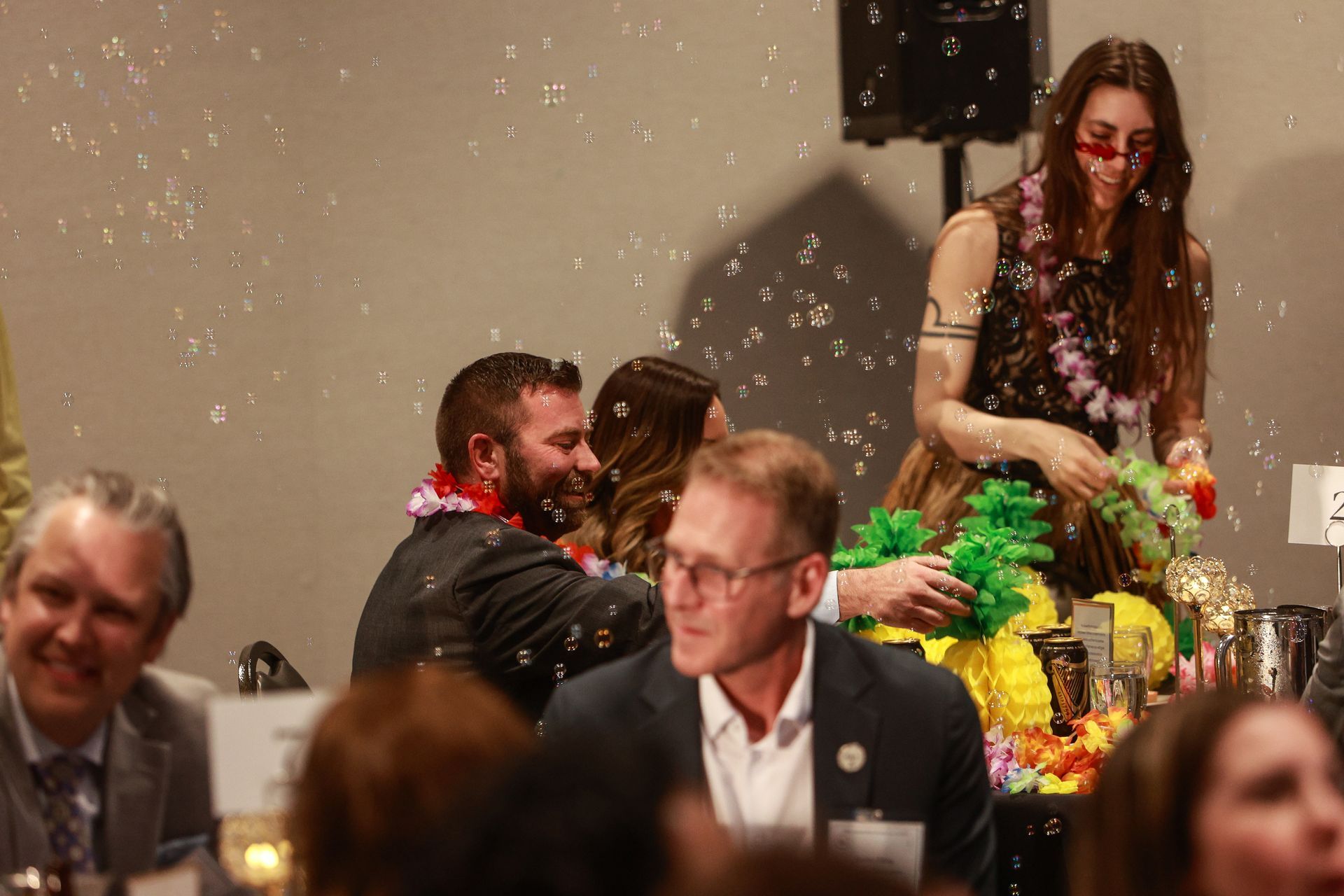 People at a festive indoor gathering with confetti, chatting around a decorated table