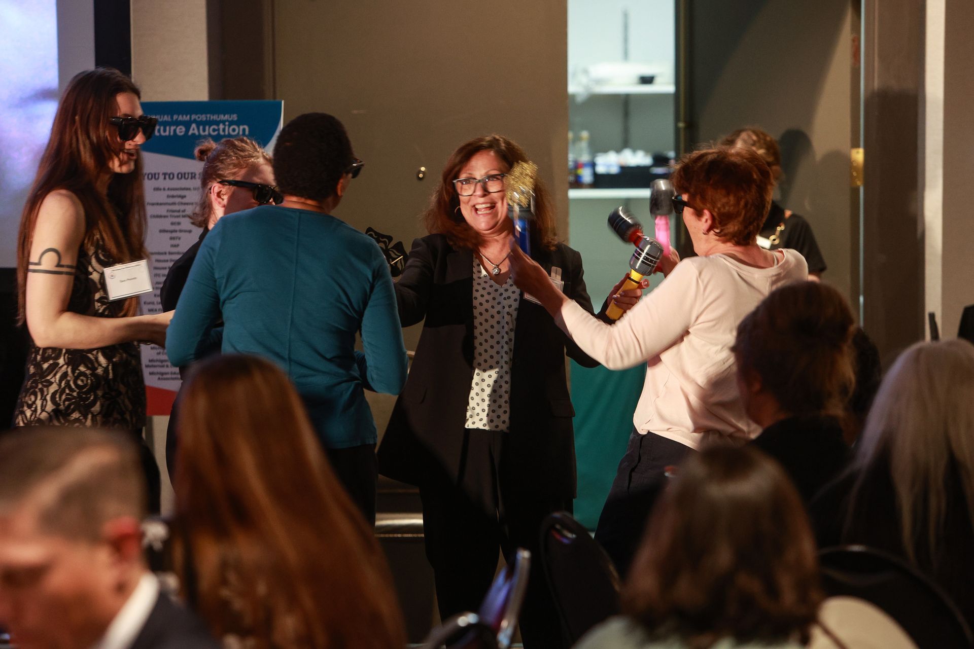 People mingling at a networking event, one woman smiling while others chat indoors.