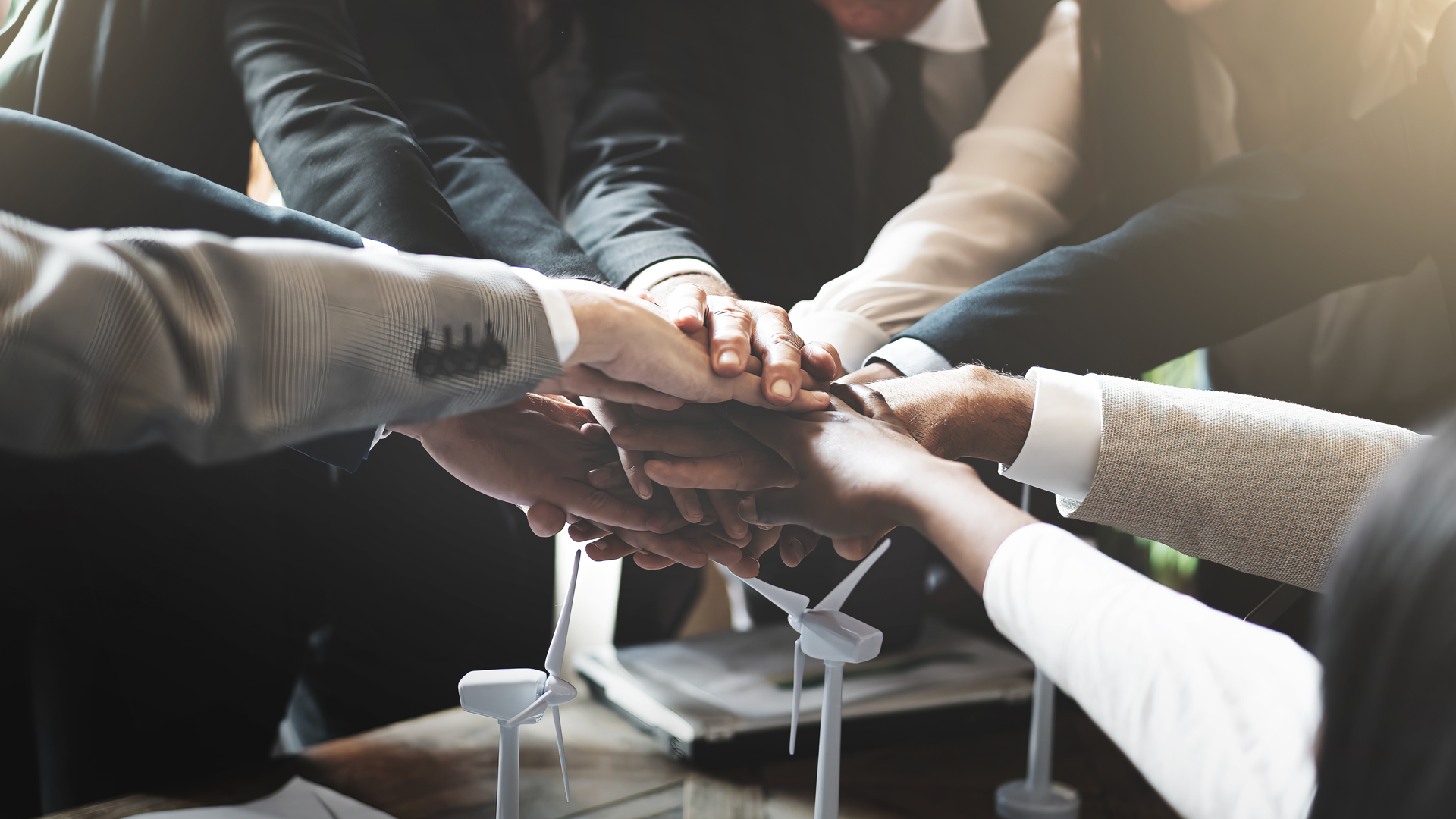 A group of people are putting their hands together in a circle.
