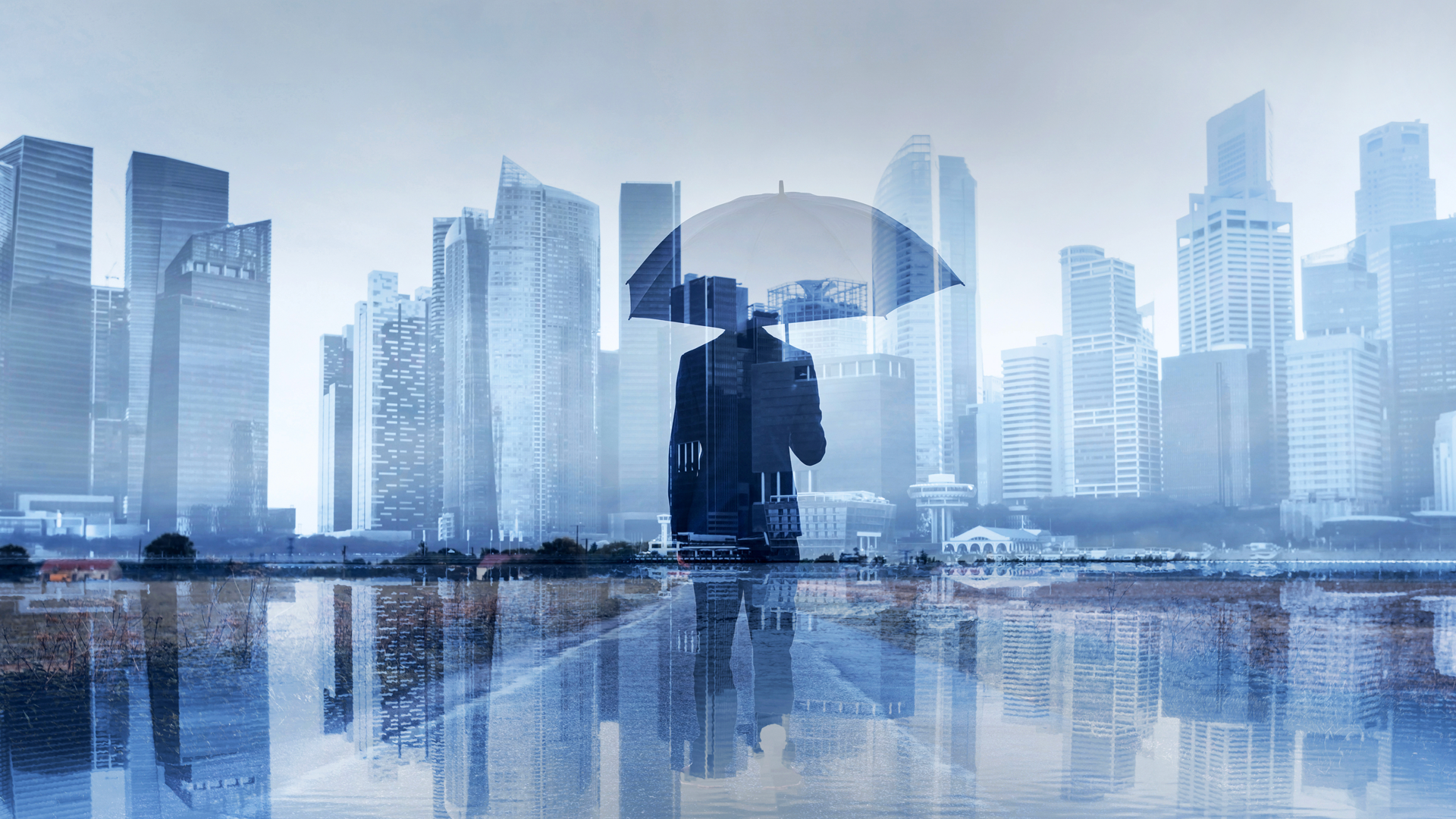 A man is holding an umbrella in the rain in front of a city skyline.