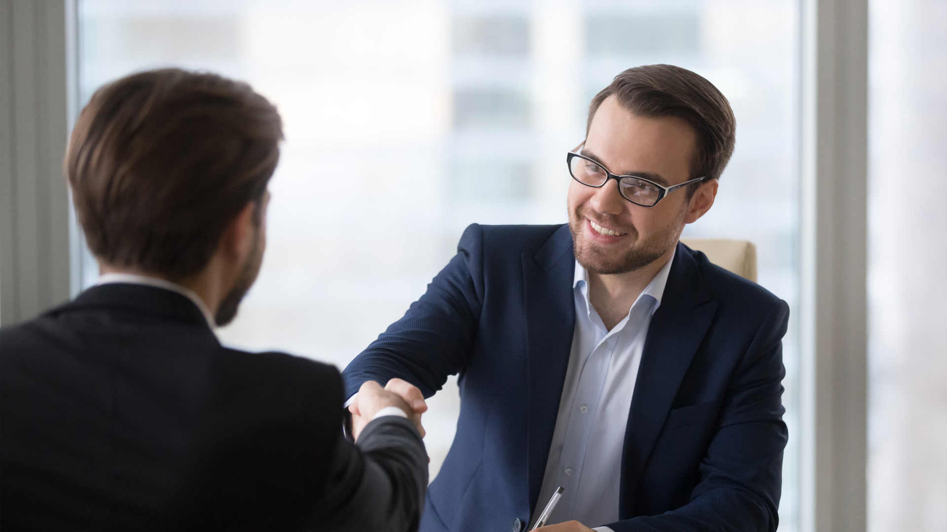 Two men are shaking hands during a job interview.