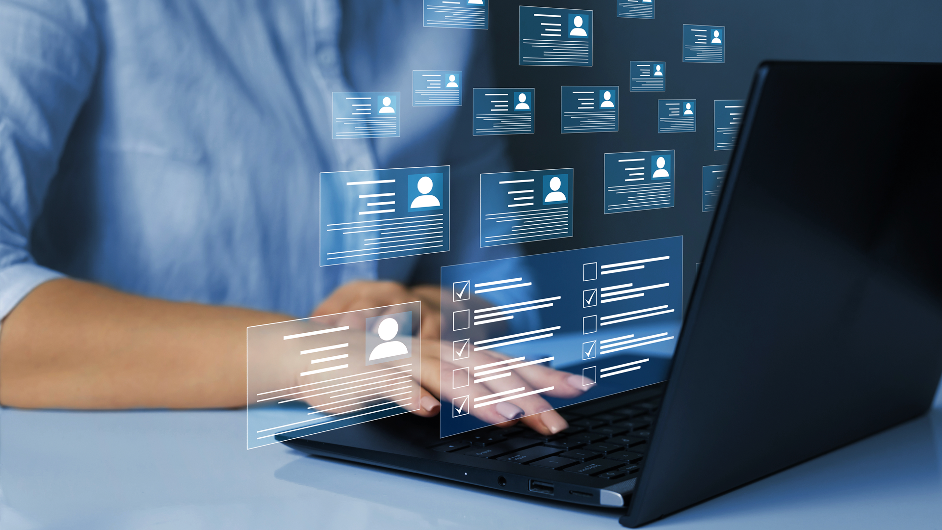 A person is typing on a laptop computer with icons coming out of the screen.