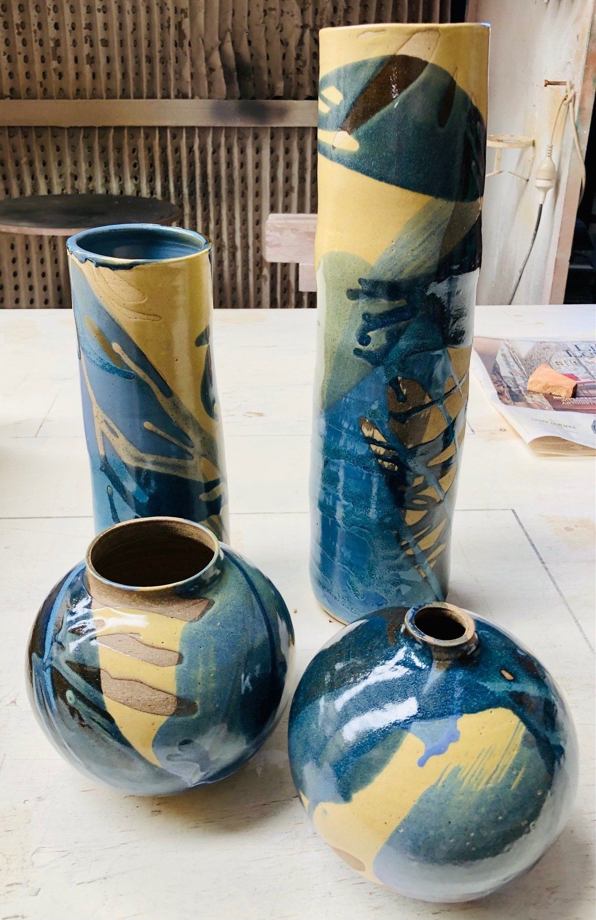 Three blue and yellow vases are sitting on a table.