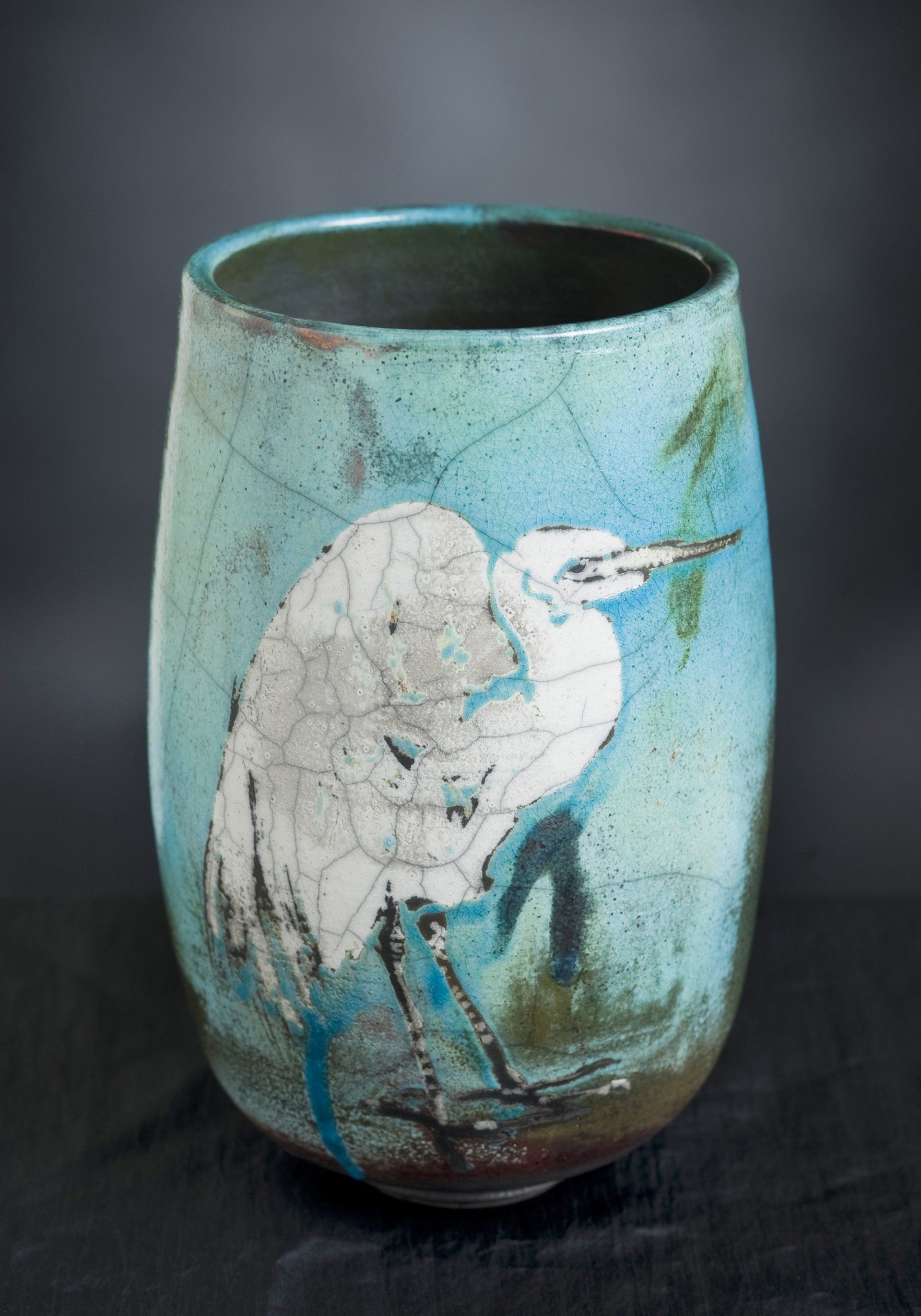 A blue vase with a bird painted on it