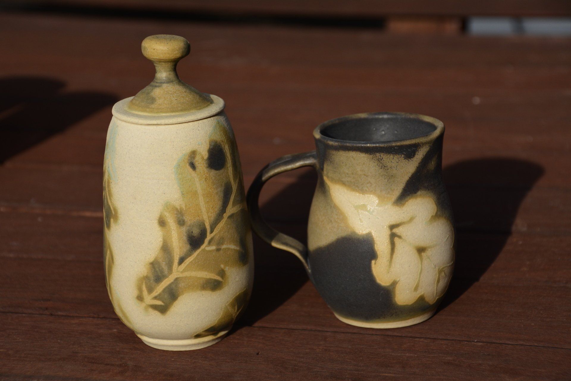 A jar and a cup are sitting on a wooden table