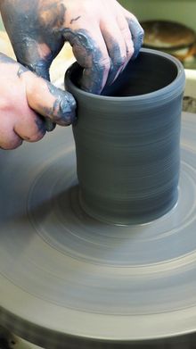 A person is making a pot on a pottery wheel.