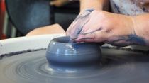 A person is making a pot on a pottery wheel.