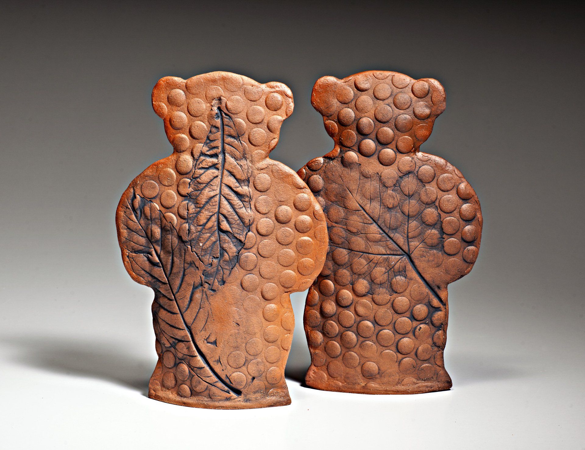 Two brown bears with leaves on them are standing next to each other