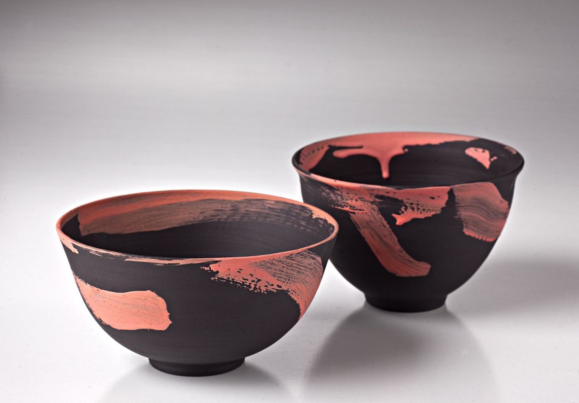 Two black and red bowls on a white surface