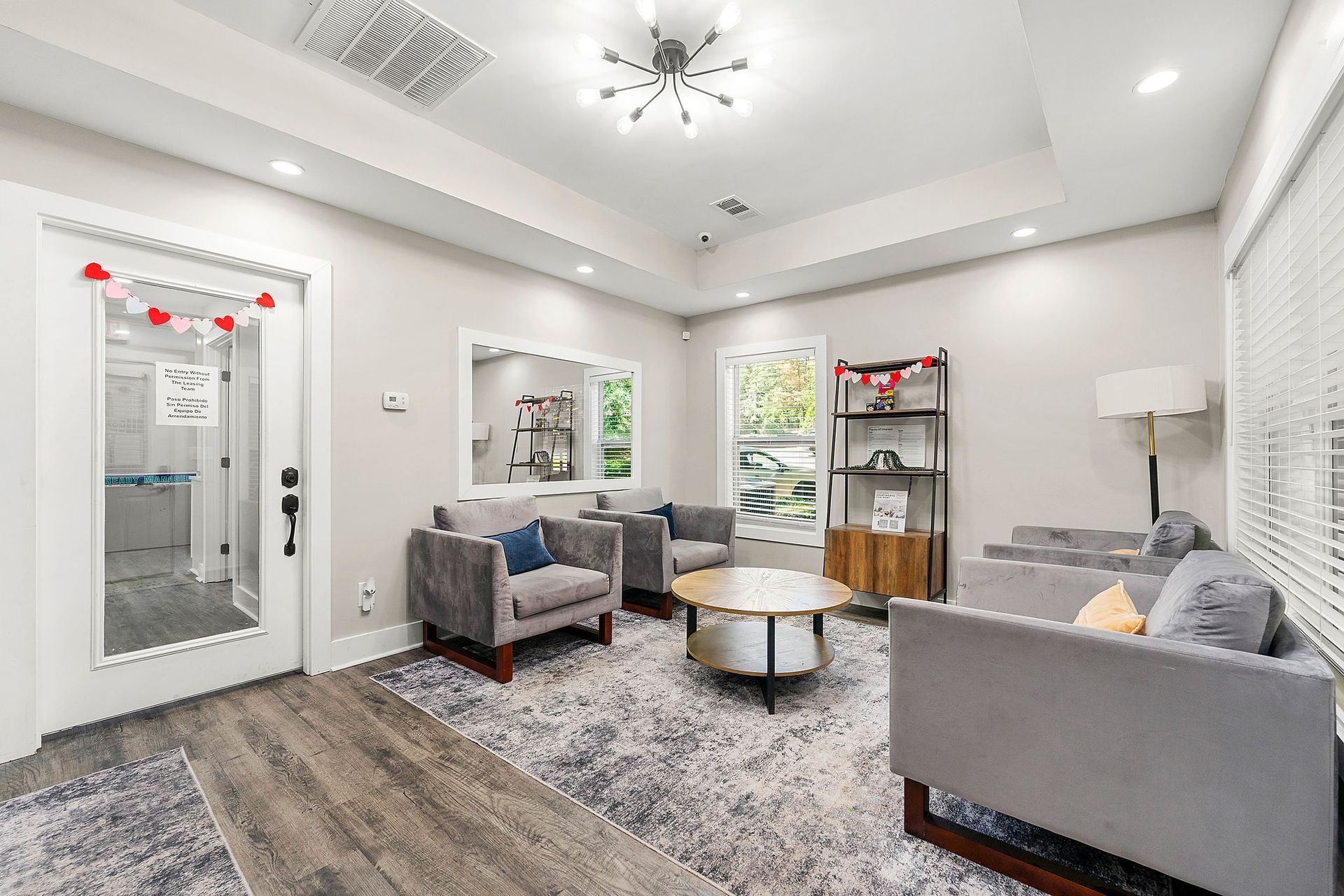 Bright modern living room with gray sofas, a shag rug, coffee table, and mirrored wall decor
