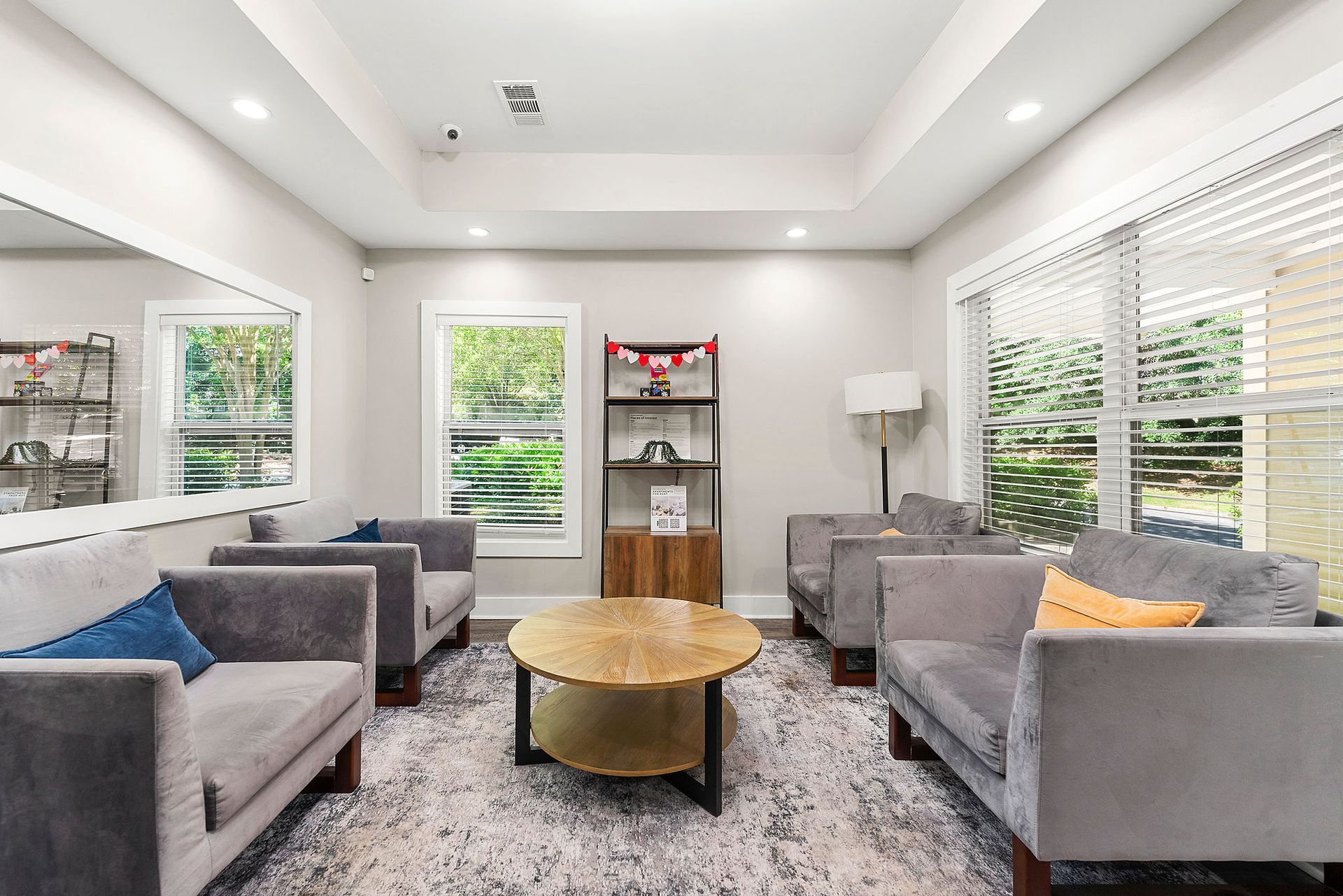 Bright modern living room with gray sofas, gold coffee table, and large windows