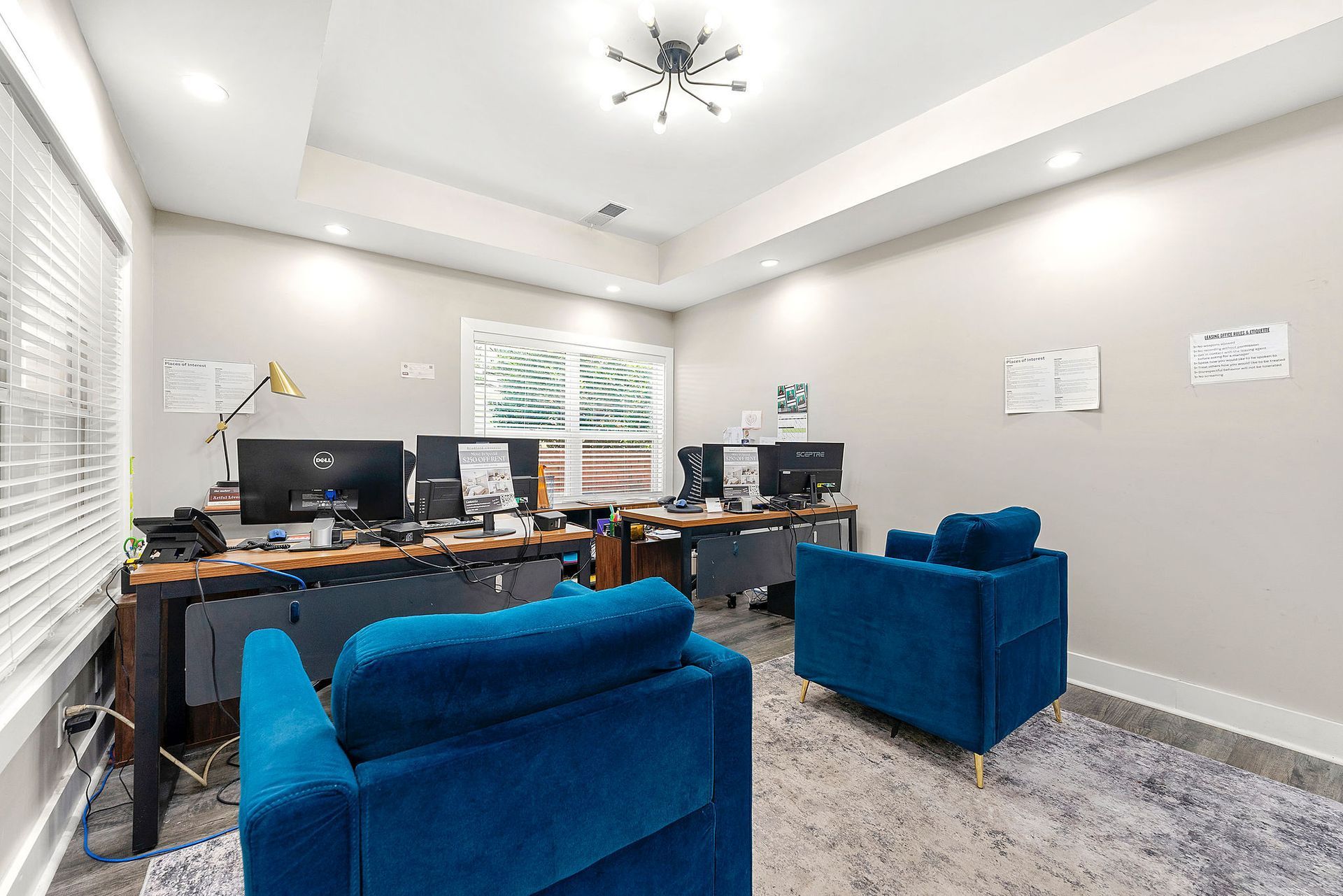 Modern office with desks, computers, blue sofas, and bright recessed lighting