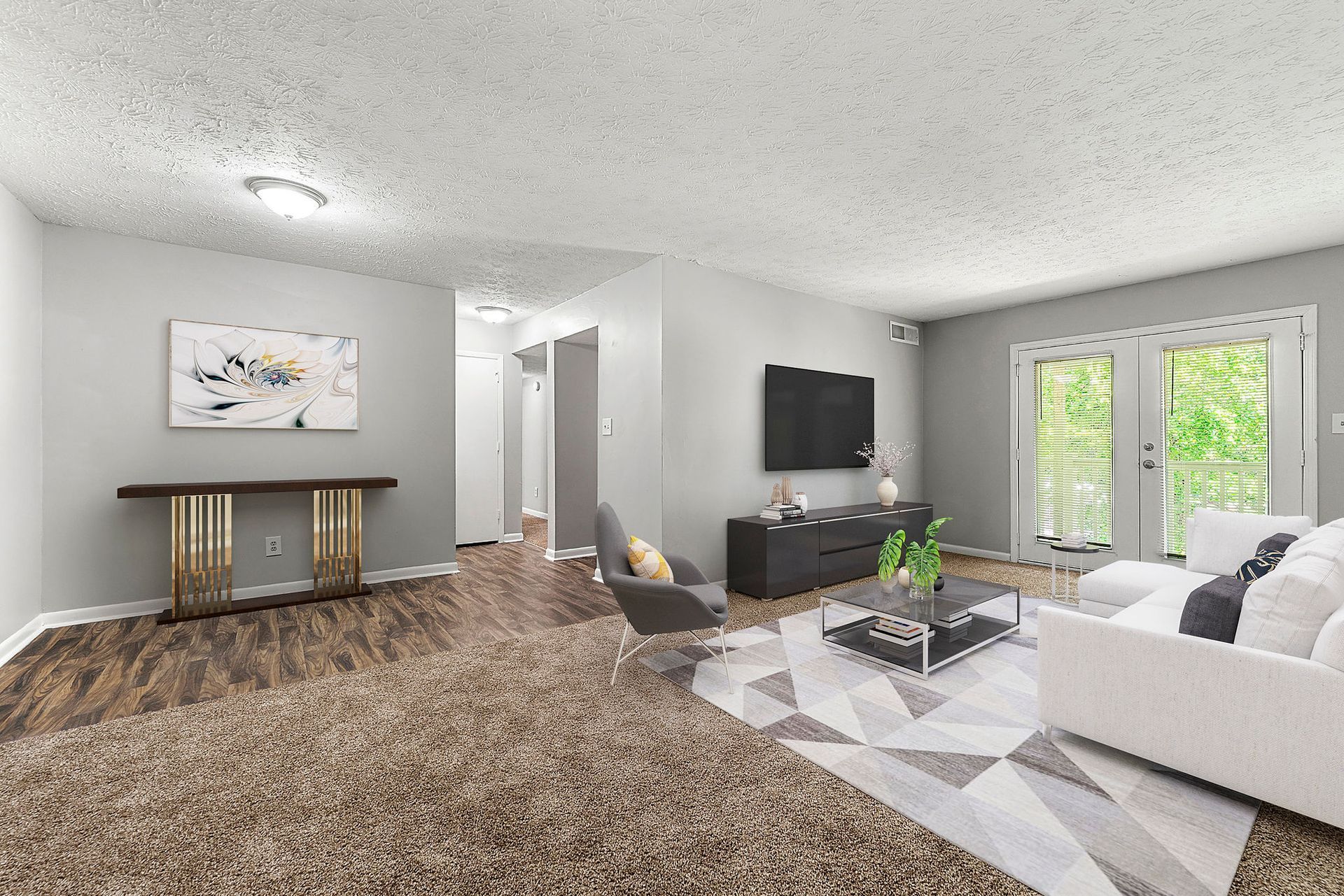 Bright living room with white walls, gray carpet, TV console, and large windows by a sofa and coffee table