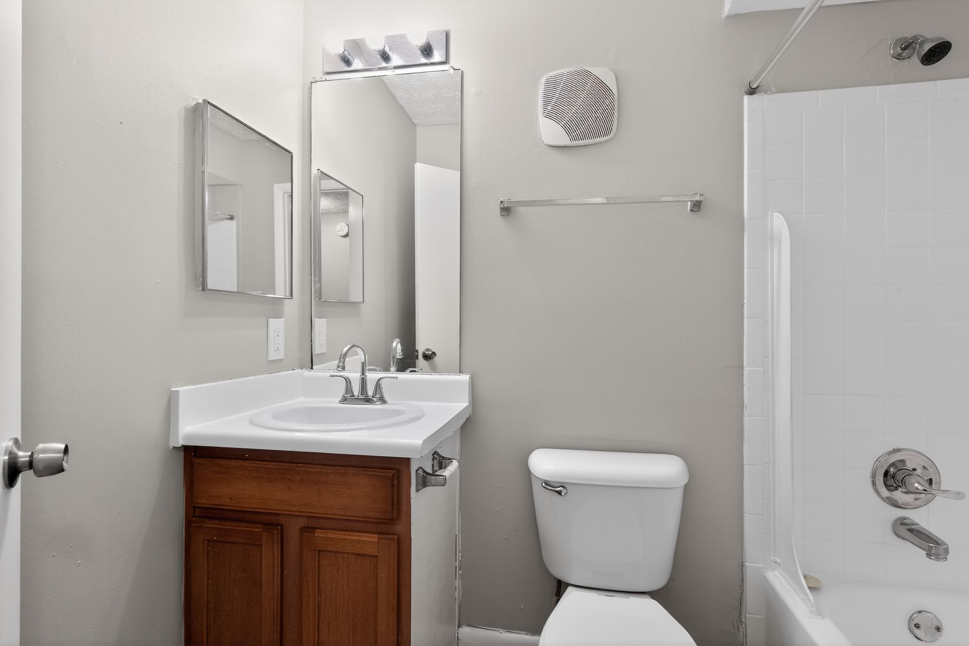 Small bathroom with vanity, mirror, toilet, and shower stall in light gray tones