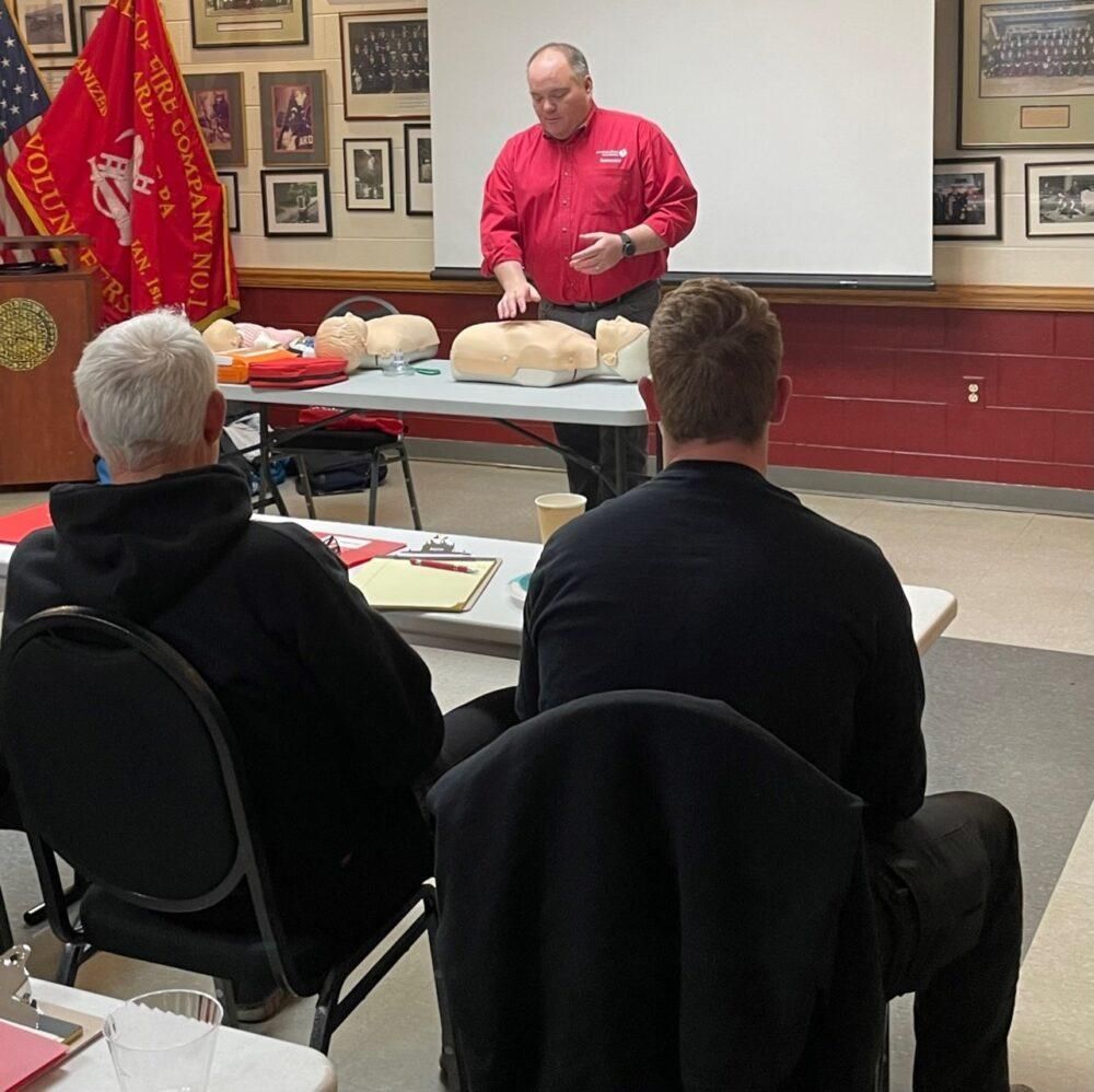 A man in a red shirt is giving a presentation to a group of people