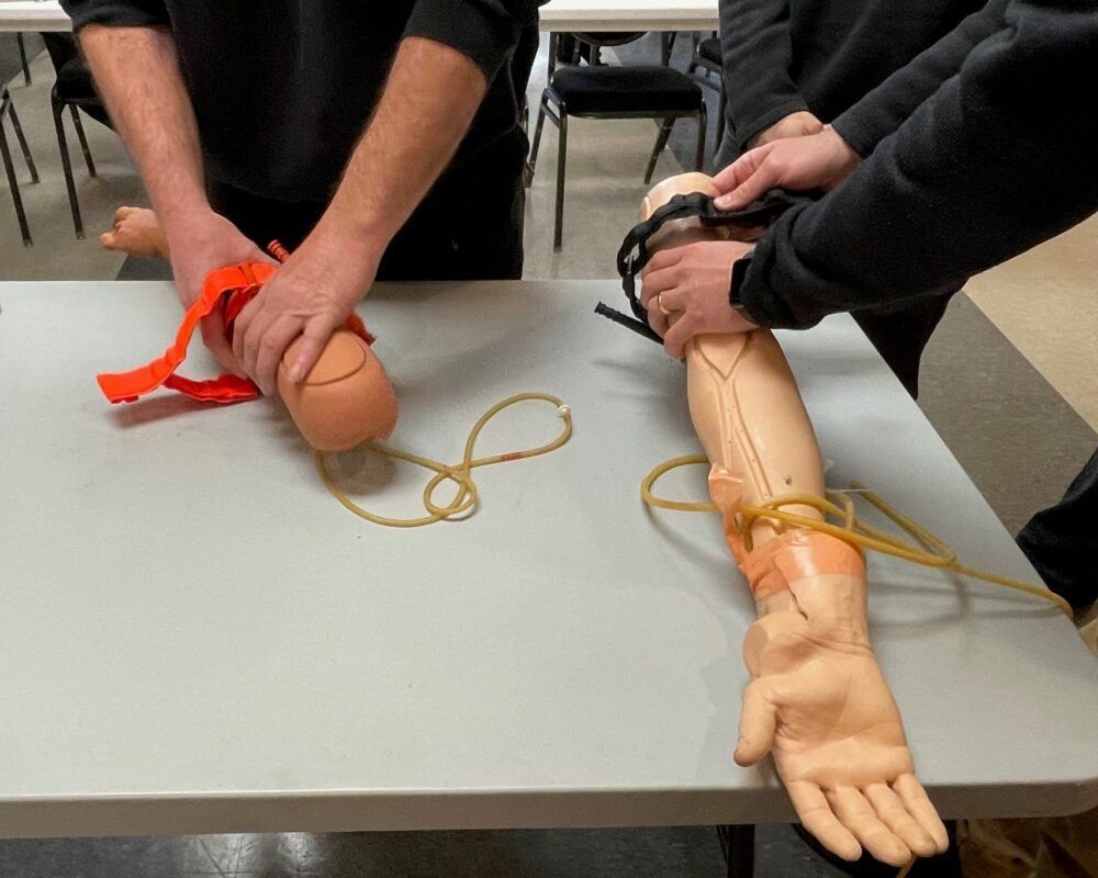 A man is putting a bandage on a mannequin arm