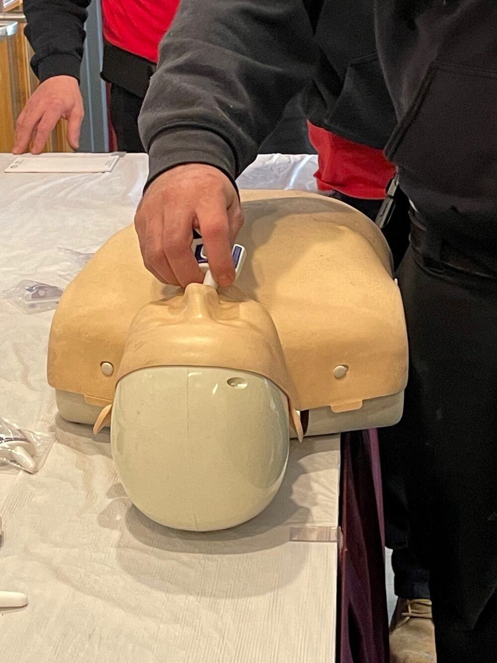 A man is using a stethoscope on a mannequin.