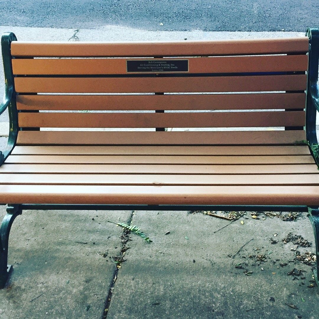 A wooden park bench with a plaque on the back