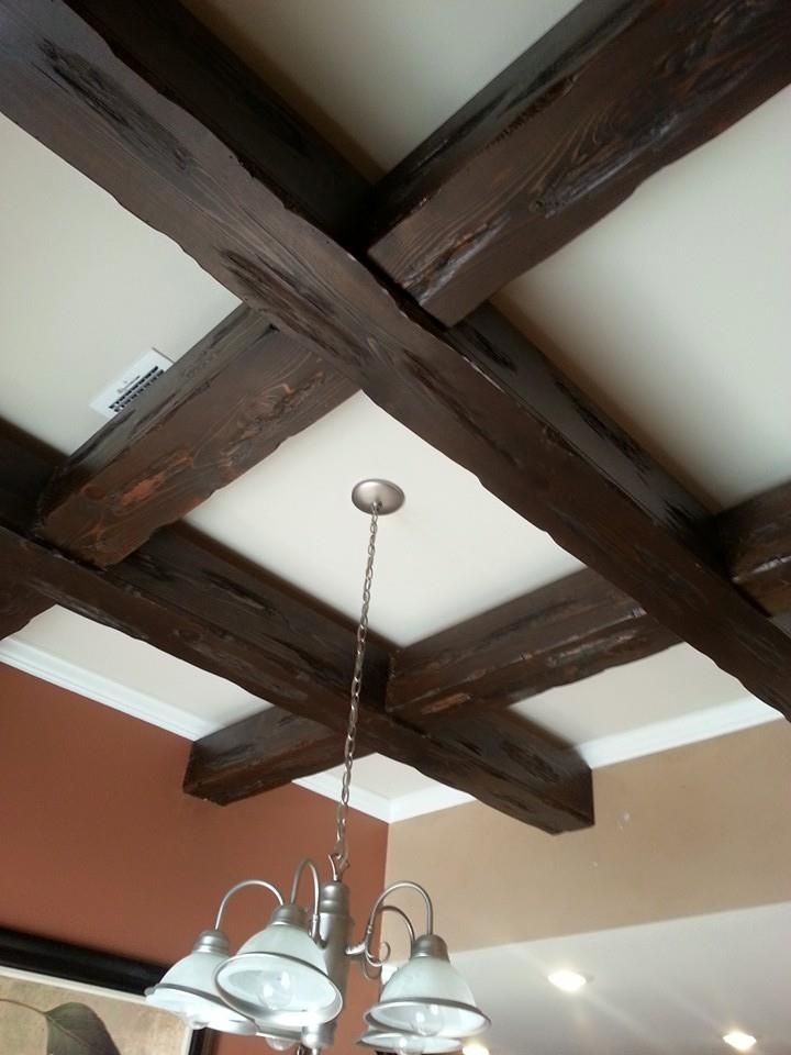 A ceiling with wooden beams and a chandelier hanging from it