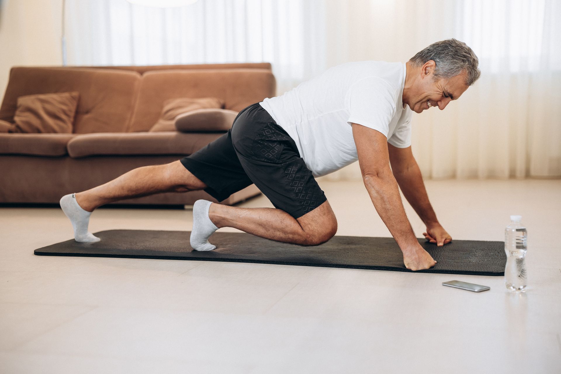 A man is doing a plank on a yoga mat in a living room.
