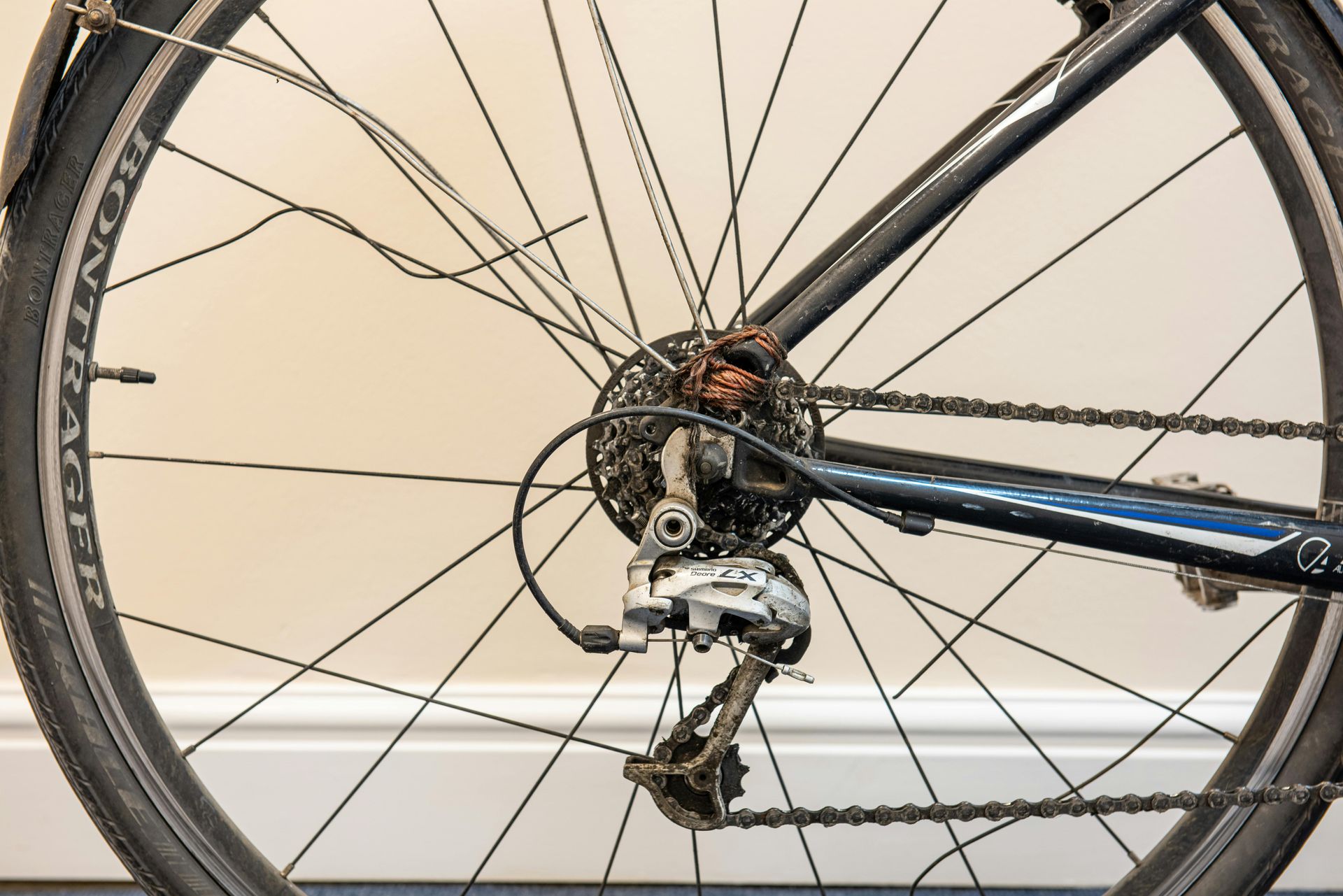 Close-up of a bicycle’s rear wheel, chain, and derailleur against a light background