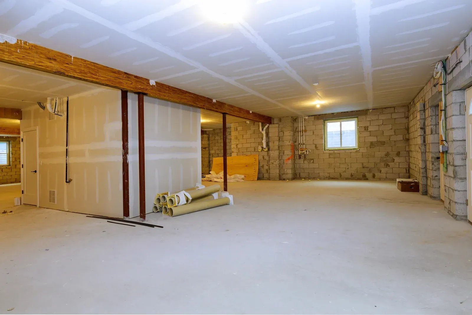 Unfinished basement interior with exposed insulation, stone walls, and construction materials on the floor