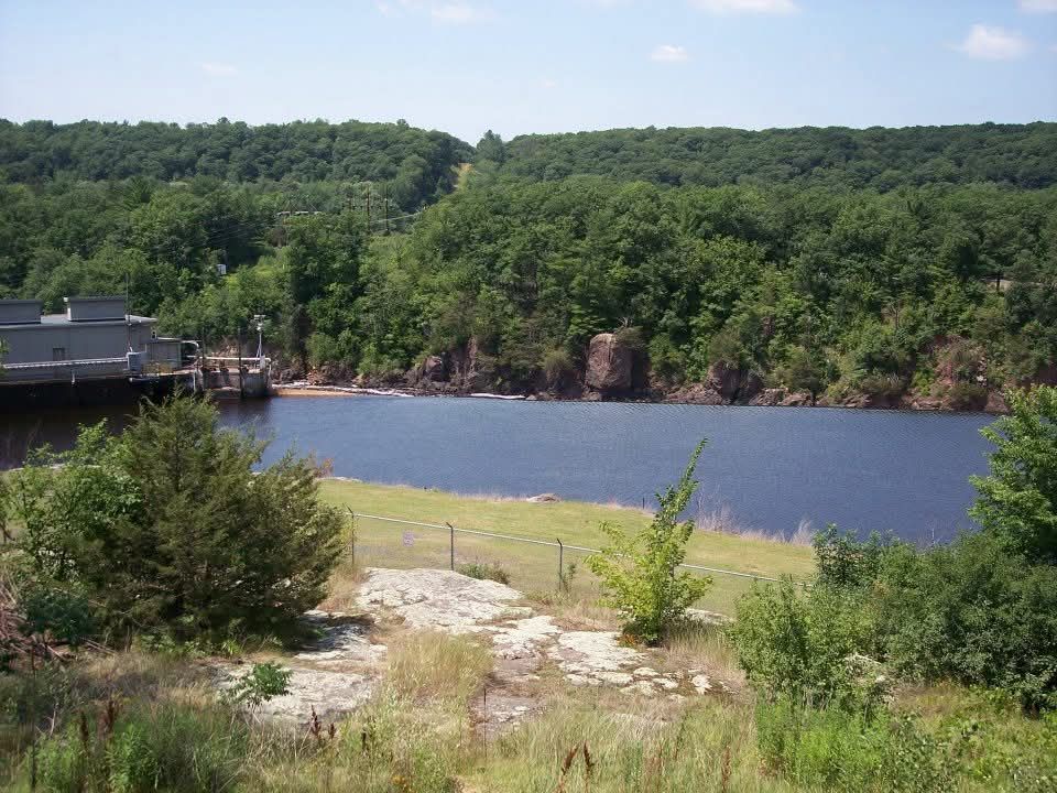 River or lake view with wooded shoreline, blue water, and a small dock on the left.
