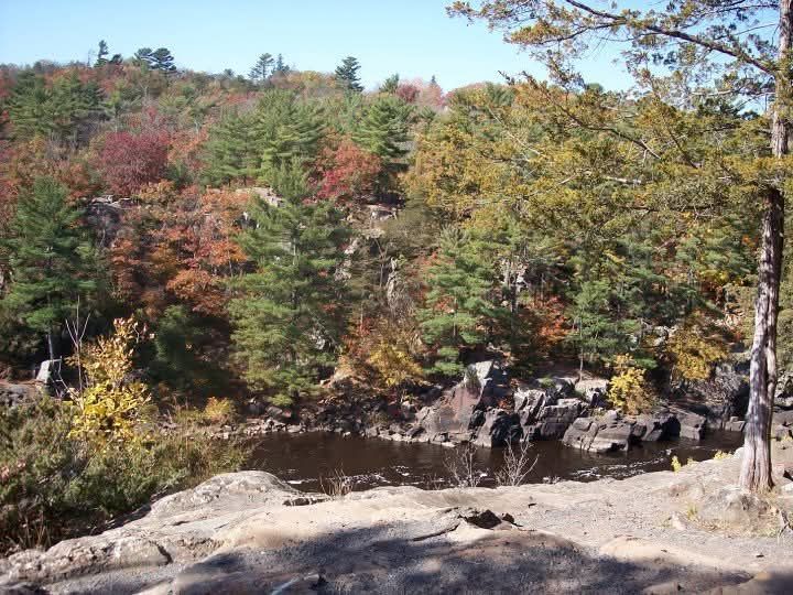 Rocky overlook above a wooded valley with autumn-colored trees and a calm river below